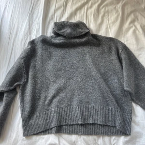 Grå polotröja från Zara - Säljer en chill grå polotröja från Zara med ribbade muddar och hög krage. Tröjan är stickad och har en loose fit som är perfekt för lager på lager. Passar dig som gillar enkel och clean stil. Fråga om du vill ha fler bilder eller info!