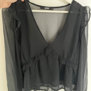 Svart blus med volang från Bikbok - Supersnygg svart blus från Bikbok i storlek S. 