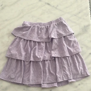 Ljuslila volangkjol från Vila - Supersöt ljuslila kjol från Vila med flera volanger och broderade spetsdetaljer. ANVÄNT EN GÅNG 