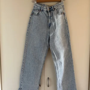 Ljusblå wide jeans med slits - Säljer ett par ljusblå jeans med breda ben och slitsar längst ner. Klassisk femficksmodell med knapp och dragkedja framtill. Jeansen har en relaxed vibe och är perfekta för dig som gillar loose fit och streetstyle. Materialet är jeans och färgen är ljusblå.