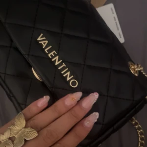 Svart quiltad axelväska från Valentino - Säljer en svart axelväska från Valentino med quiltad design och guldfärgade detaljer Väskan är en liten model och köpt för en månad sen men kommer inte till användning. Inga skador💘Kan gå ner till 850 helst 900 max vid snabb och smidig affär!! 💘