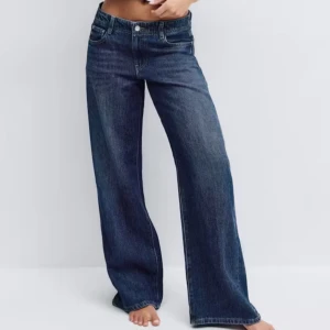 Blå wide jeans från Gina tricot - Ett par low wide jeans från Gina tricot i nytt skick, de är lågmidjade och är i storlek 40. Nypris är 499 