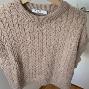 Beige kabelstickad tröja NA-KD - Säljer en beige kabelstickad tröja från NA-KD i storlek S. Tröjan har korta ärmar, rund hals och ett chunky stickat mönster🤎🤎