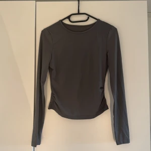 Långärmad croppad topp i tre färger - Säljer tre stilrena långärmade croppade toppar i svart, vit och grått. Alla är i mjuk och stretchig polyester med rund hals och diskret rynkning vid sidorna. Perfekt för dig som gillar minimalistisk look och vill ha ett plagg som funkar till många outfits.