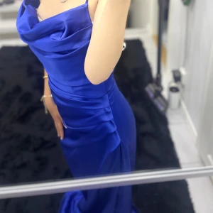Blå långklänning med draperad urringning - Säljer en elegant marinblå långklänning med draperad urringning och smala axelband. Klänningen har en figurnära passform och är tillverkad i ett glansigt satinliknande material som ger en lyxig känsla. Perfekt för dig som vill sticka ut med en stilren och modern look. Har använt 1 gång och köpte klänningen för 5000 kr. (PRISET KAN DISKUTERAS!)💙✨