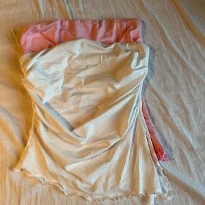 2 tube tops - en rosa och en vit tube topp som jag säljer för att rensa garderoben, båda har en slit på sidan längst ner. dom kanske ser skrynkliga ut men det är dom inte när man har dom på sig, har aldrig använt någon av det