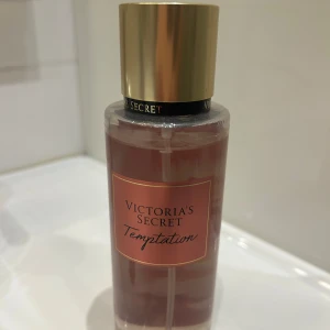 Victoria's Secret Temptation mist - Fräsch body mist från Victoria's Secret i doften Temptation. Flaskan är genomskinlig med rosaröd etikett och guldigt lock. Doften har inslag av saftigt äpple och ökenblomma. Inte mycket som används 