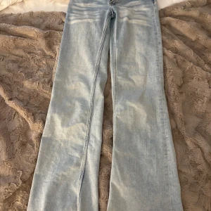 Bootcut ljusblå jeans från Cheap Monday - Säljer ett par ljusblå bootcut jeans från Cheap Monday med klassisk femficksdesign och coolt logopatch med döskalle bak. Jeansen har en snygg tvätt och raka ben som blir bredare nedtill. Perfekt för dig som gillar retrovibe och streetstyle.