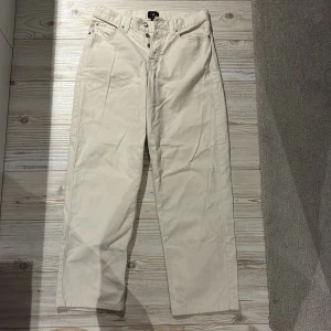 Beige loose fit jeans från HM - Snygga beige jeans från H&M med rak passform. Byxorna har även knappgylf. Perfekt för dig som gillar en clean och stilren look. Passar till sneakers eller boots. Legat längst ner i garderoben, därav skrynkliga. 