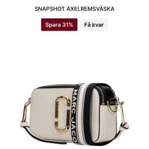 Snapshot axelväska från Marc Jacobs - Säljer en snygg Snapshot axelväska från Marc Jacobs i vit och svart med guldfärgade detaljer. Väskan har en bred, randig axelrem med logotyp och dragkedja upptill. Perfekt storlek för mobilen och det viktigaste, med cool design och lyxig känsla. Använd max 10 gånger och väskan är äkta. Priset börjar på 3000kr så skriv till mig ett förslag pris