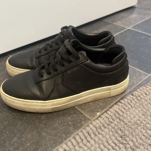 Svarta sneakers från Axel Arigato - Snygga svarta sneakers från Axel Arigato Skorna är gjorda i skinn och har svarta snören samt diskret guldfärgad logga på sidan. Nypris 2500kr. Det är en liten blå fläck på vänster sko, därav lågt pris. Pris går att diskutera! Skriv vid frågor eller fler bilder 💓