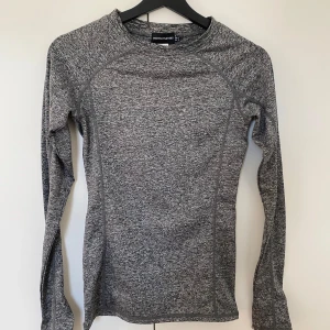 Grå långärmad träningströja - Slimmad grå långärmad träningströja från PrettyLittleThing. Tröjan har ett melerat mönster och är tillverkad i mjukt syntetmaterial som andas. 