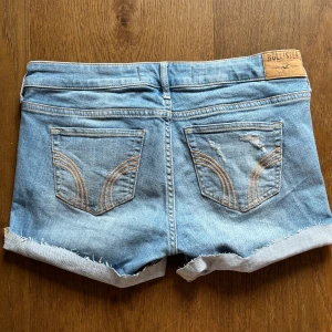 Ljusblå jeansshorts från Hollister - Snygga ljusblå jeansshorts från Hollister med klassisk femficksdesign, slitna detaljer och uppvikta benslut. Lågmidjade och fint skick! Skulle säga att de passar storlek S ungefär.
