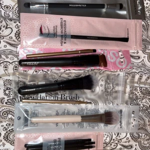 Nytt set med sminkborstar från olika märken - Säljer ett kit med nya flera sminkborstar totalt 14 st från M.Cosmetics, Needs, Lindex och Apolosophy. Innehåller foundationborste, ögonskuggsborste, ögonbrynsborste och precisionborstar. Borstarna har svarta, vita och guldiga handtag och mjuka syntetiska borst. Perfekt för att skapa snygga looks och detaljer.