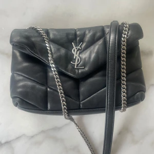 Ysl puffer bag Loulou  - Klassiska Yves Saint Laurent (YSL) LouLou guiltad väska med silverfärgade detaljer.  Väskan har en vadderad design och en ikonisk YSL-logotyp på framsidan. Snygga kedjeremmen i kombo m läderrem för att bäras på axeln eller crossbody.  Insidan är fodrad och har en ficka.  Varsamt använd,  Köpt på Vestiaire  Har tyvärr inte kvar låda och dustbag, men annan dustbag kan så klart skickas med för bästa förvaring.