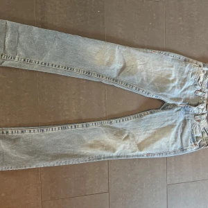 True Religion ljusblå jeans  - Säljer ett par ljusblå jeans från True Religion med klassiska broderade bakfickor och röda detaljer vid sömmarna. Modellen har rak passform och låg midja. Jeansen är tillverkade i bomull och har en snygg tvättad look som passar till sneakers.