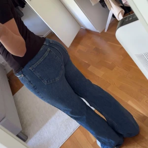  blå raka högmidjade jeans - Säljer ett par klassiska blå högmidjade jeans med rak passform. Jeansen har, raka ben som blir vidare nertill och femficksdesign. Knappt använda. 