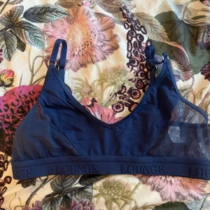 Mörkblå meshbh från Lounge - Snygg mörkblå bh från Lounge med meshdetaljer på sidorna och justerbara axelband.  Finns tillhörande trosor, därav är priset högre. Vill du bara ha bhn kan du ge prisförslag!