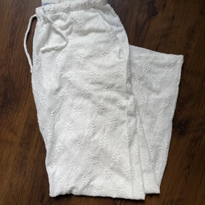 Vita frottébyxor från Madlady - Supermjuka vita byxor från Madlady i frotté med snyggt strukturmönster. De har resår och snörning i midjan för skön passform och raka ben. Perfekta för chill dagar eller när du vill ha något bekvämt men ändå stilrent.