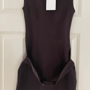 Oanvänd Mörkbrun ärmlös klänning från Zara - Snygg mörkbrun klänning från Zara i figurnära modell med ärmlös design och rund hals. Klänningen har en detalj med bälte i midjan.❤️