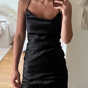 Satin klänning  - Supersnygg svart kortklänning i satin från monki med tunna axelband som korsas i ryggen. Klänningen är aldrig använd och är i storlek 32