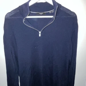 Mörkblå stickad tröja Jack & Jones - Snygg mörkblå stickad tröja från Jack & Jones med half zip-dragkedja i halsen. Tröjan har långärmad design och är tillverkad i mjukt material som passar perfekt för kyliga dagar. Enkel och stilren look som funkar till jeans eller chinos.
