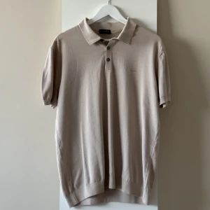 SAND Copenhagen beige pikétröja - Beige pikétröja från SAND med korta ärmar och mjuk textur. Ny och utan defekter. Logotyp på bröstet. Storlek XL. 100% bomull. Nypris: 800kr