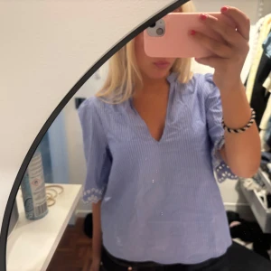 Blåvit randig blus  - Supersöt blå och vit randig blus med v-ringning och trekvartsärm. Ärmsluten har broderade spetsdetaljer som ger en extra touch. Från Hm. Aldrig använd endast provad storlek S