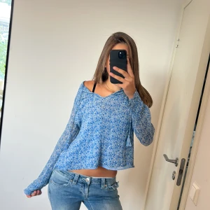 Blå croppad stickad tröja - Säljer en blåmelerad croppad stickad tröja med offshoulder och lång ärm. Tröjan har en avslappnad loose passform och ett snyggt mönster som ger en cool vibe. Perfekt för dig som gillar att sticka ut med din stil.