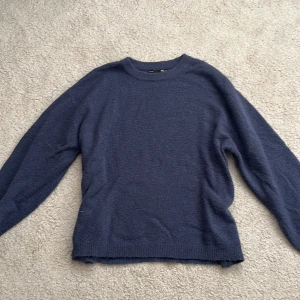 Blå stickad tröja från 157 - Mysig blå stickad tröja från 157 i storlek M. Tröjan har en rund halsringning och långa ärmar med ribbade muddar. Perfekt för kyliga dagar och enkel att matcha med jeans eller cargo. Materialet är mjukt och ger en chill vibe.