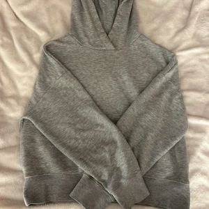 Grå hoodie från Amisu i storlek M - Säljer en enkel och stilren grå hoodie från Amisu i storlek M. Tröjan har huva, långa ärmar och breda muddar vid ärmslut och nederkant. Mjuk insida och klassisk passform, perfekt för chill dagar eller när du vill vara extra comfy. hål i armhålan och sliten därav väldigt billigt pris