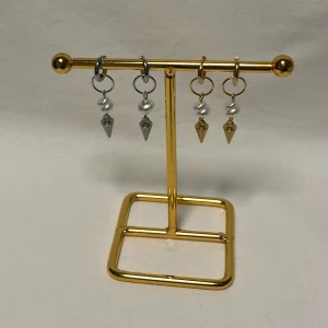 Örhängen med pärlor och spetsiga hängen - Coola örhängen med rund ring i silver eller guld, dekorerade med en vit pärla och ett spetsigt hängsmycke i metall. Perfekt för dig som gillar edgy detaljer och vill sticka ut med både guld och silver i din stil.