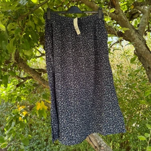 Blommig mörkblå långkjol från MyWear - Snygg långkjol från MyWear i mörkblått med små blommor i vitt och ljusblått. Kjolen har en rak och luftig passform med resår i midjan för extra komfort. Perfekt för dig som gillar en chill och feminin stil. Storlek L. Helt ny med tags/ prislapp fortfarande kvar. 