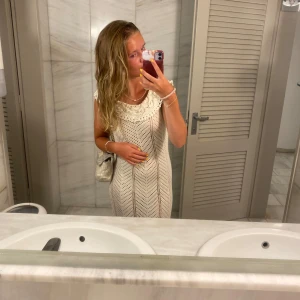 Vit virkad strandklänning - Säljer en superfin vit virkad klänning med rund hals och spetsdetaljer upptill. Nu är sommaren snart slut men den kan vara perfekt till nästa, eller om man ska åka utomlands!! Säljer då den är för liten för mig😇