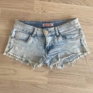 Ljusblå jeansshorts från Miss RJ - Snygga ljusblå jeansshorts från Miss RJ med fransiga kanter och klassisk femficksdesign. Shortsen har låg midja och slitna detaljer för en cool, avslappnad look. Perfekta för varma sommardagar och festivaler.