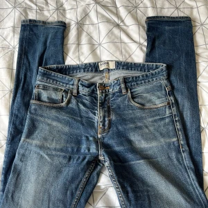 Blå jeans från Dobber W32 L34 - Snygga blå jeans från Dobber med klassisk femficksdesign och slitna detaljer för en cool look. Jeansen har rak passform och normal midja, med kontrastsömmar och läderpatch bak. Perfekt för dig som gillar tidlös denimstil.