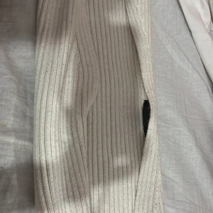 Vita ribbade stickade kort kofta (AMISU) - Säljer en vit stickade kortkorta från Amisu i storlek XS/S. Koftan har ribbat mönster och är supermjuka och sköna, perfekta för en chill dag hemma eller när du vill vara extra cozy. Elastisk midja för bästa komfort.