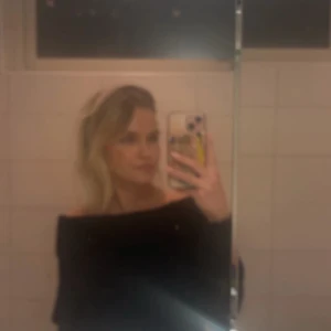 Mörkgrå offshoulder stickad tröja - Säljer en svart stickad tröja med offshoulder-modell och bred ribbad kant upptill. Tröjan har lång ärm och är perfekt för dig som vill ha en stilren men ändå trendig look. Supermjuk och skön att bära till både jeans och kostymbyxor.