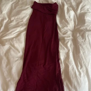Vinröd långkjol - Säljer en elegant vinröd lånkjol. kjolen har en smickrande, figurnära passform och är perfekt för dig som vill sticka ut med en stilren look. Materialet känns mjukt och följsamt mot kroppen. Perfekt till höst och vintern🩷