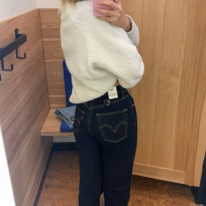 Levi's ribcage straight mörkblå high waist - Mörkblå Levi's ribcage straight jeans med klassisk rak passform och hög midja. Snygga kontrastsömmar och ikonisk läderpatch bak. Jeansen är i kraftigt denimtyg i 100% bomull och har fem fickor och knappar. De är längre i benen än vad L32 brukar vara. Skriv om ni har något fråga!🤍