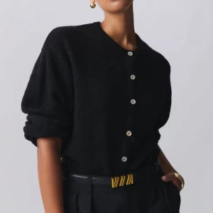 Svart stickad kofta med knappar - Svart, mysig stickad kofta från Gina Tricot med rund hals och knappar framtill. Koftan har en loose passform och långa ärmar, perfekt att slänga på sig när det är kyligt. Enkel och stilren design som funkar till allt.