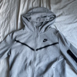 Grå Nike Tech Fleece - En fin zip hoodie som värmer hösten. Jag har haft den i 6 månader men den är inte alls mycket använd. Barnstorlek L , 147-158 