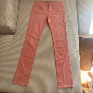 Rosa jeansbyxor från IKKS Denim - Snygga rosa jeansbyxor från IKKS Denim med klassisk femficksmodell och cool stjärndetalj på myntfickan. Byxorna har raka ben och normal passform, tillverkade i mjuk bomullsdenim. Perfekta för dig som vill sticka ut med färg i vardagen.