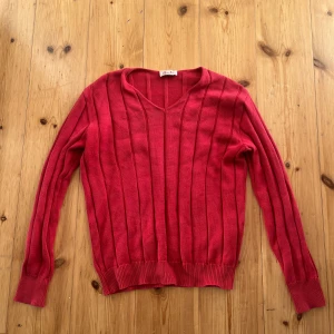 Snygg röd stickad tröja - Röd långärmad tröja från Marie Valois med snygg v-ringning och ribbad struktur. Tröjan har ett klassiskt snitt och är perfekt för dig som gillar färg. Passar till både jeans och kjol för en chill look.