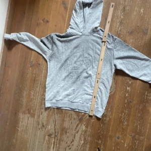 Grå hoodie Acne Studios Stockholm - Snygg grå hoodie från Acne Studios med tryck på ryggen: 'Acne Studios STOCKHOLM 1996'. Klassisk passform med huva och långa ärmar. Perfekt för en chill och stilren look. Mjuk och skön i bomullsmix.