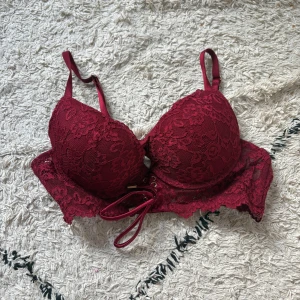 Vinröd spetsbh från New Yorker - Supersnygg vinröd spetsbh från New Yorker med vadderade kupor och spetsdetaljer. Snygg snörning framtill och justerbara axelband. Perfekt för dig som vill ha en feminin och trendig look på stranden eller vid poolen.