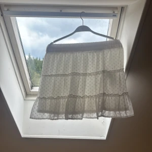 Vit prickig volangkjol FB Sister XS - Supersöt vit kortkjol från FB Sister i storlek XS. Kjolen har flera lager volanger och ett prickigt mönster som ger en lekfull vibe. Resår i midjan för skön passform. Perfekt för dig som gillar en romantisk och trendig stil.