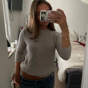 Ljusgrå stickad tröja med trekvartsärm - Säljer en ljusgrå stickad tröja med trekvartsärmar. Perfekt att matcha med jeans för en chill och stilren look.