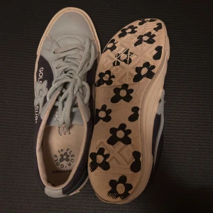 Golf le Fleur x Converse sneakers blå/grå - Unika Golf le Fleur x Converse sneakers i blått och ljusgrått skinn med blommönster på sulan. Låga med snörning och broderad logga på sidan. Perfekta för dig som vill sticka ut med coola detaljer och klassisk Converse-vibe.