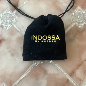 Silverfärgat armband från Indossa - Snyggt armband i silverfärg från Indossa by Sweden. Armbandet har en cool, flätad kedjedesign som ger en chunky och trendig look. Perfekt accessoar för att lyfta din outfit. Levereras i svart tygpåse med guldfärgad logga.